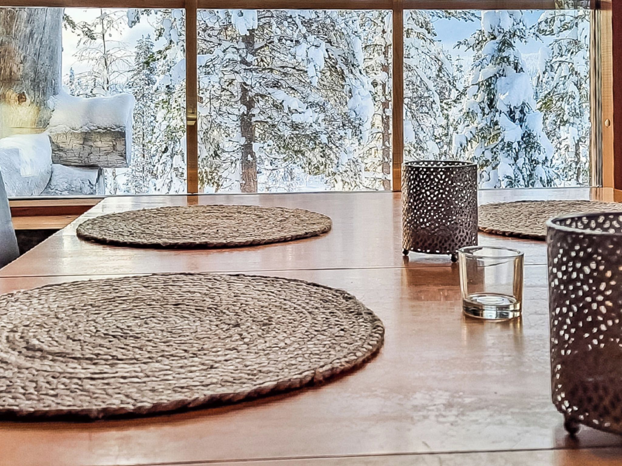Une table à manger avec des sets de table en fibres tressées, un verre et un chandelier.