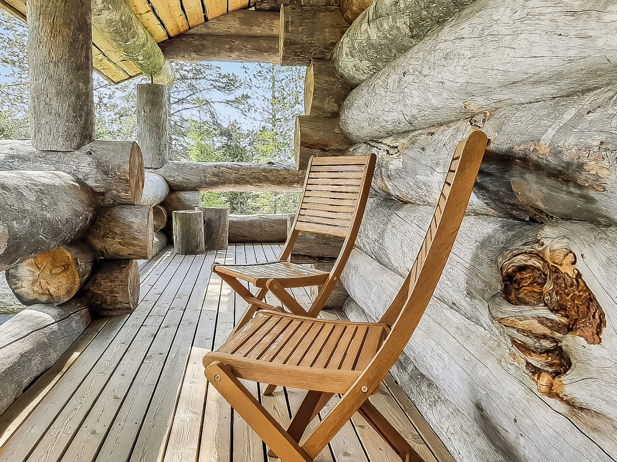 A wooden deck with two wooden lounge chairs, surrounded by logs and a rustic cabin interior.