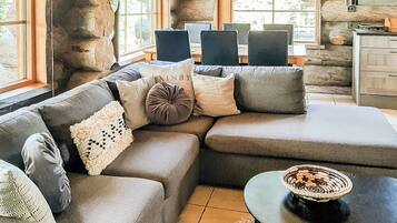 A modern living room with a sectional sofa, a small round table, and a stone wall.
