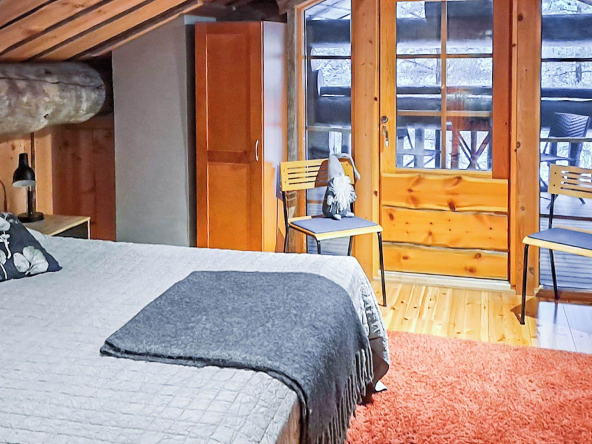 Une chambre confortable avec un lit, une chaise et une petite table. Une porte en bois donne accès à un espace extérieur.