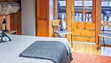 Une chambre confortable avec un lit, une chaise et une petite table. Une porte en bois donne accès à un espace extérieur.