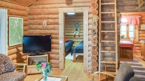 A log cabin with a TV, a sofa, a dining table, and a staircase. - Vacation home 5816 by Interhome (Äänekoski)