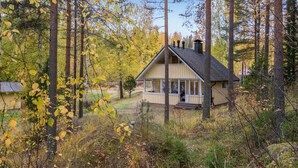 A cabin with a porch, surrounded by trees and autumn foliage.