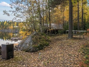 Una cabaña junto al lago con un muelle, rodeada de follaje otoñal y un lago tranquilo.