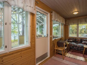 Puinen mökki, jonka sisätiloissa on ruokailutila ja sohva.