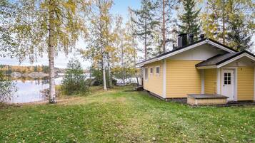 Ein gelbes Blockhaus mit Steg, umgeben von Bäumen und einem See.