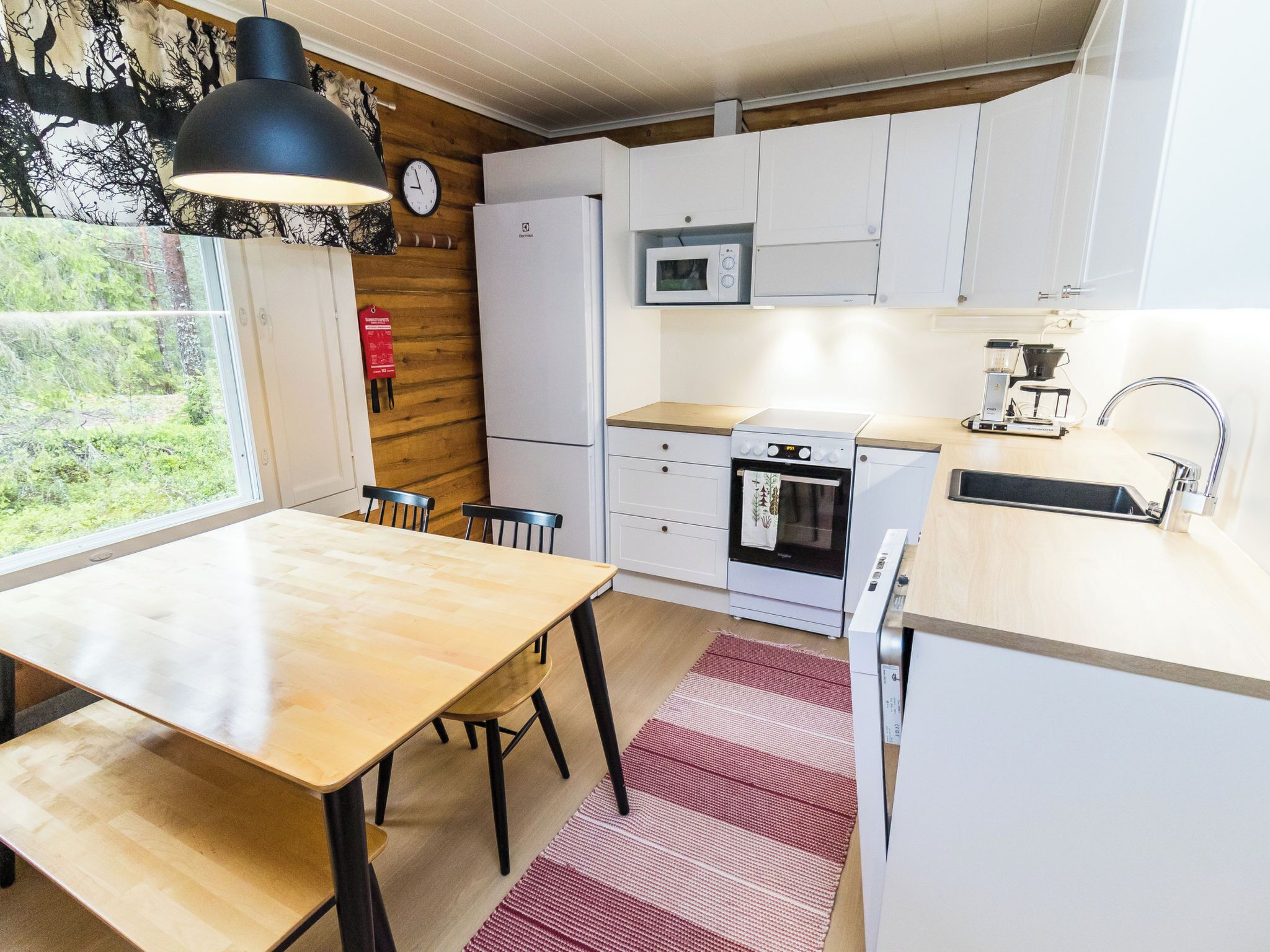 Uma cozinha compacta com mesa, cadeiras, micro-ondas, forno e cafeteira.