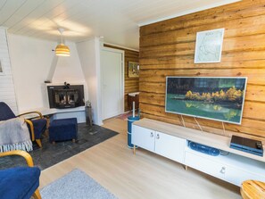 A cozy living room with a fireplace, a mounted television, and a wooden wall.