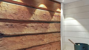 A room with wooden panel walls, a white ceiling, and a blue bucket on the floor.