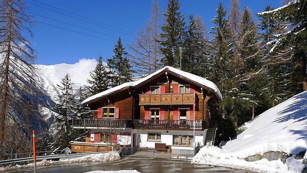 A chalet with a balcony, surrounded by snow-covered mountains and trees. - Lärchenheim by Interhome (St Niklaus)