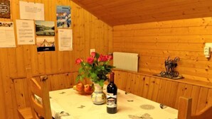 A wooden cabin interior with a dining table set for two, a vase with flowers, and a bottle of wine. - Lärchenheim by Interhome (St Niklaus)