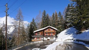 A wooden chalet with a balcony, surrounded by snow-covered trees and a clear sky. - Lärchenheim by Interhome (St Niklaus)