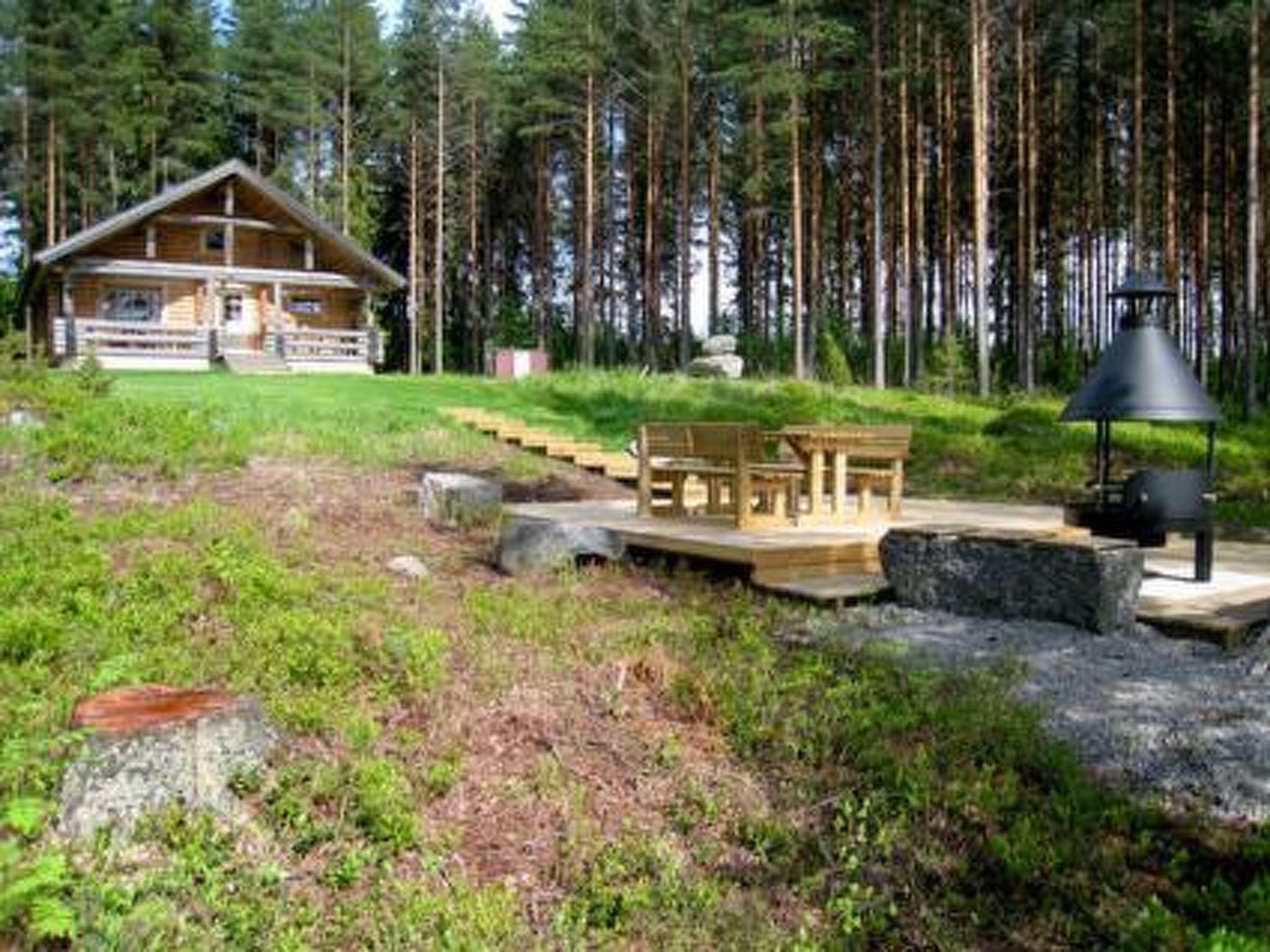 Una cabaña con terraza, rodeada de bosque.