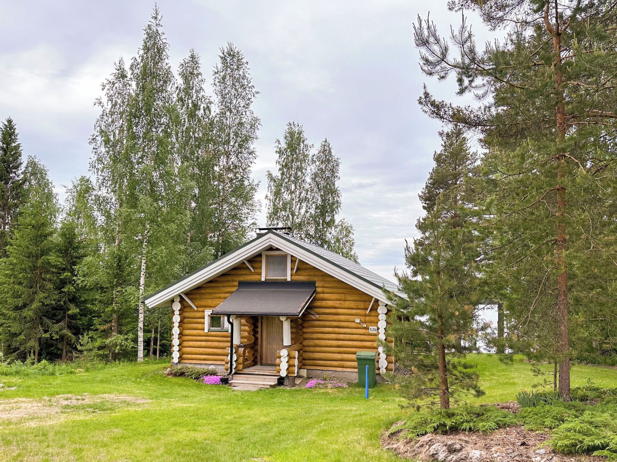 A log cabin with a front porch, surrounded by trees.