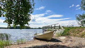A boat on a rocky shore with a wooden fence and trees in the background. - Suviranta by Interhome (Lapinlahti)