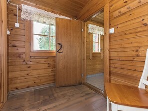 A wooden cabin interior with a single door, a window, and a chair. - Kasilahti by Interhome (Ikaalinen)