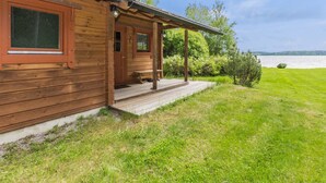 Une cabane en bois avec une véranda, une porte et une fenêtre.