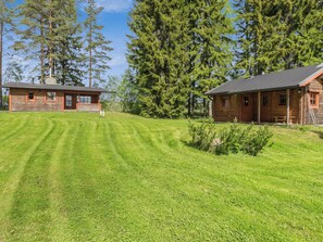 A two-story log cabin with a well-maintained lawn and tall trees in the background. - Kasilahti by Interhome (Ikaalinen)