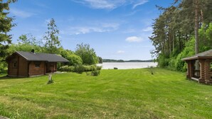 Une cabane avec une terrasse, une pelouse et une vue sur le lac.