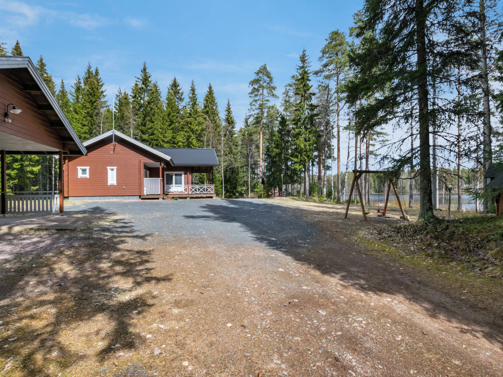 Mökki, jossa on katettu kuisti ja aidattu alue, jossa on keinuteline.
