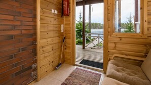 A cabin interior with a wooden interior, a fire extinguisher, a broom, and a view of a deck and lake outside. - Metsäpirtti by Interhome (Parkano)