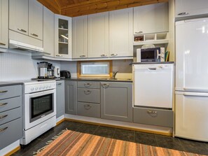 A kitchen with white cabinets, a stove, a microwave, and a refrigerator. - Metsäpirtti by Interhome (Parkano)