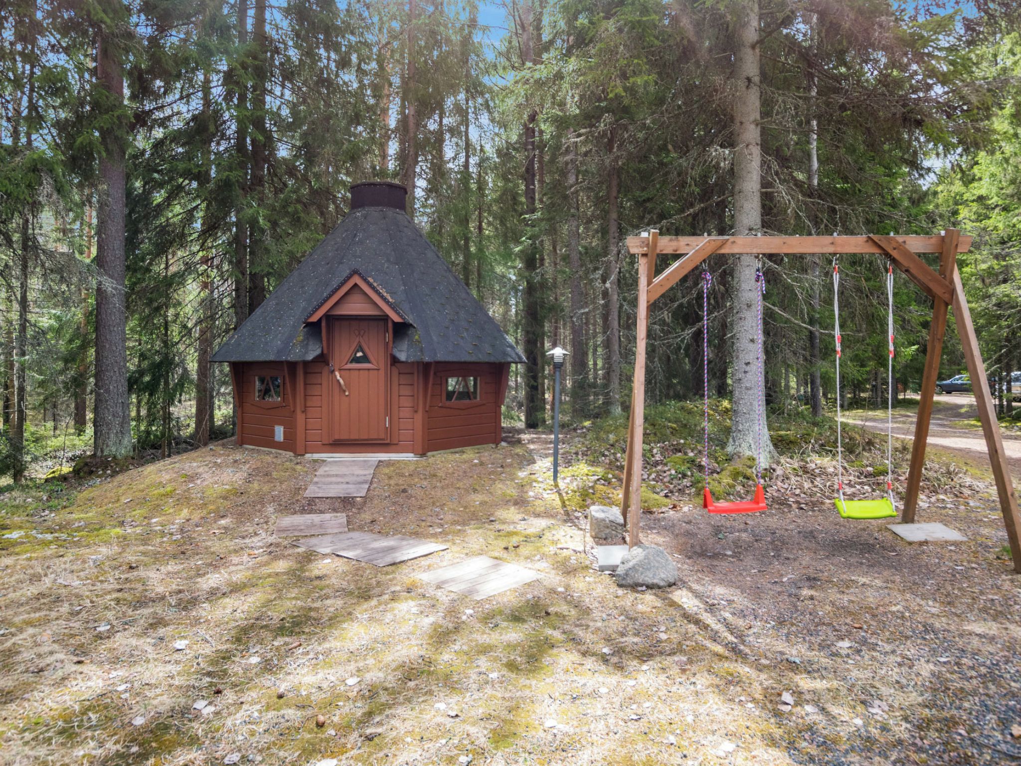 A cabin with a thatched roof, surrounded by a forest.