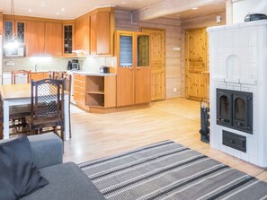 Een moderne keuken met houten keukenkastjes, een zithoek met een bank en stoelen, en een open haard.