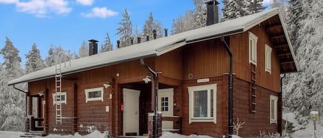 En træhytte med veranda, skorsten og en dør med teksten "Aventurini".