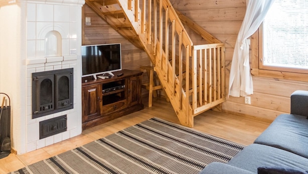 A cozy cabin interior with a wooden staircase, a fireplace, a television, and a sofa. - Klz 11. jade by Interhome (Sotkamo)