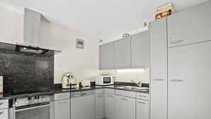 A modern kitchen with grey cabinets, a built-in oven, a microwave, and a coffee maker. - Hemmadi by Interhome (Churwalden)