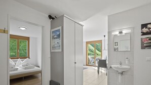 A modern hotel room with a bed, a bathroom with a sink and mirror, and a view of a garden through a sliding door. - Hemmadi by Interhome (Churwalden)