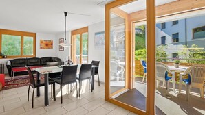 A modern living room with a glass door leading to an outdoor patio. - Hemmadi by Interhome (Churwalden)