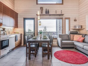 Una cocina moderna con comedor, una alfombra roja y un sofá gris.