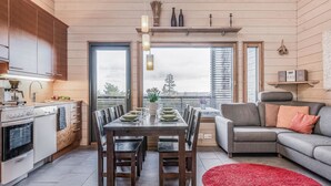 Une cuisine moderne avec un coin repas, un canapé gris et un tapis rouge.