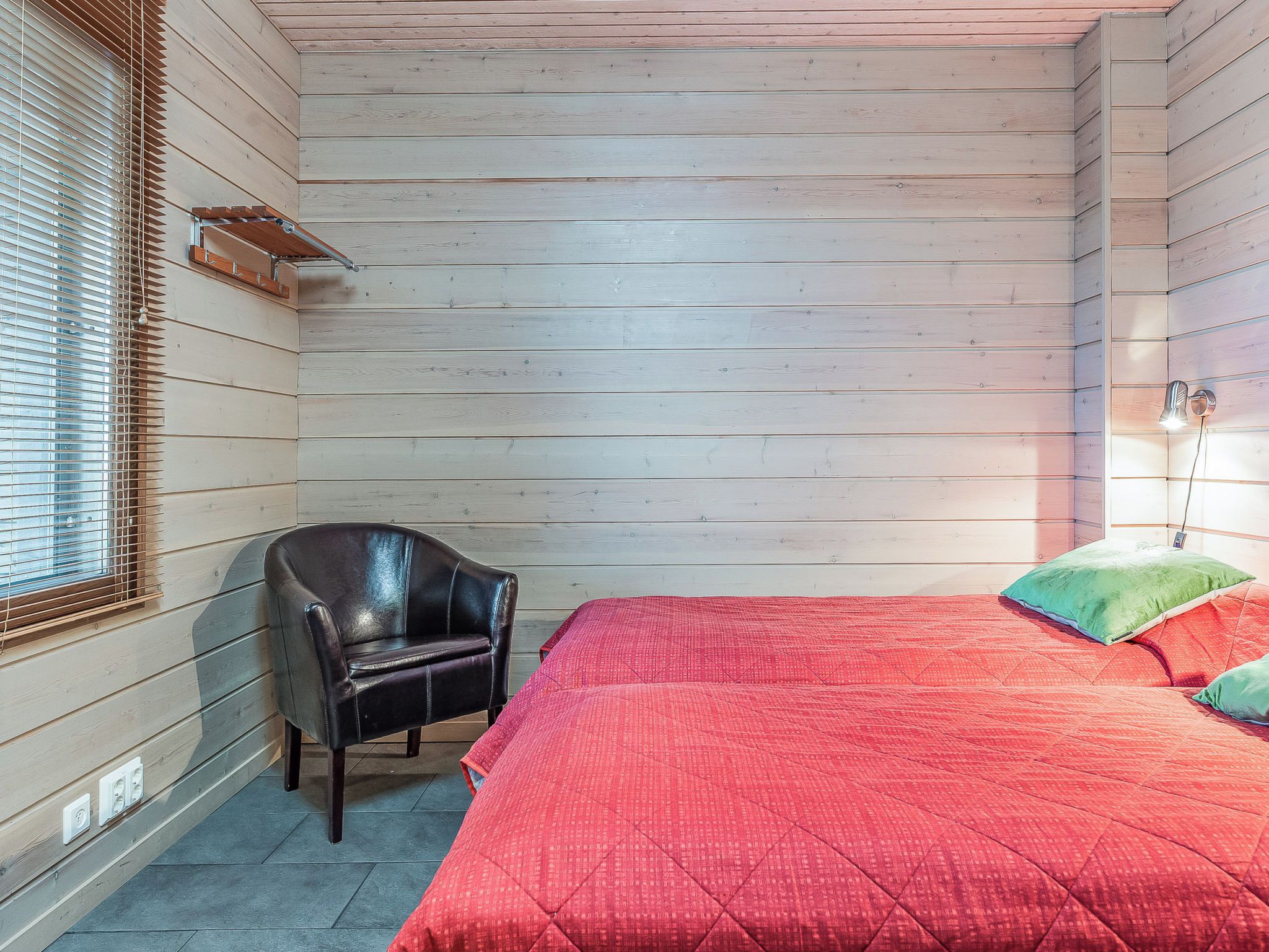 A room with a bed, a chair, and a window with blinds.