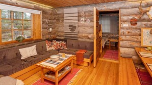 A cozy log cabin interior with a sofa, a small table with a bowl, and a wooden bench.