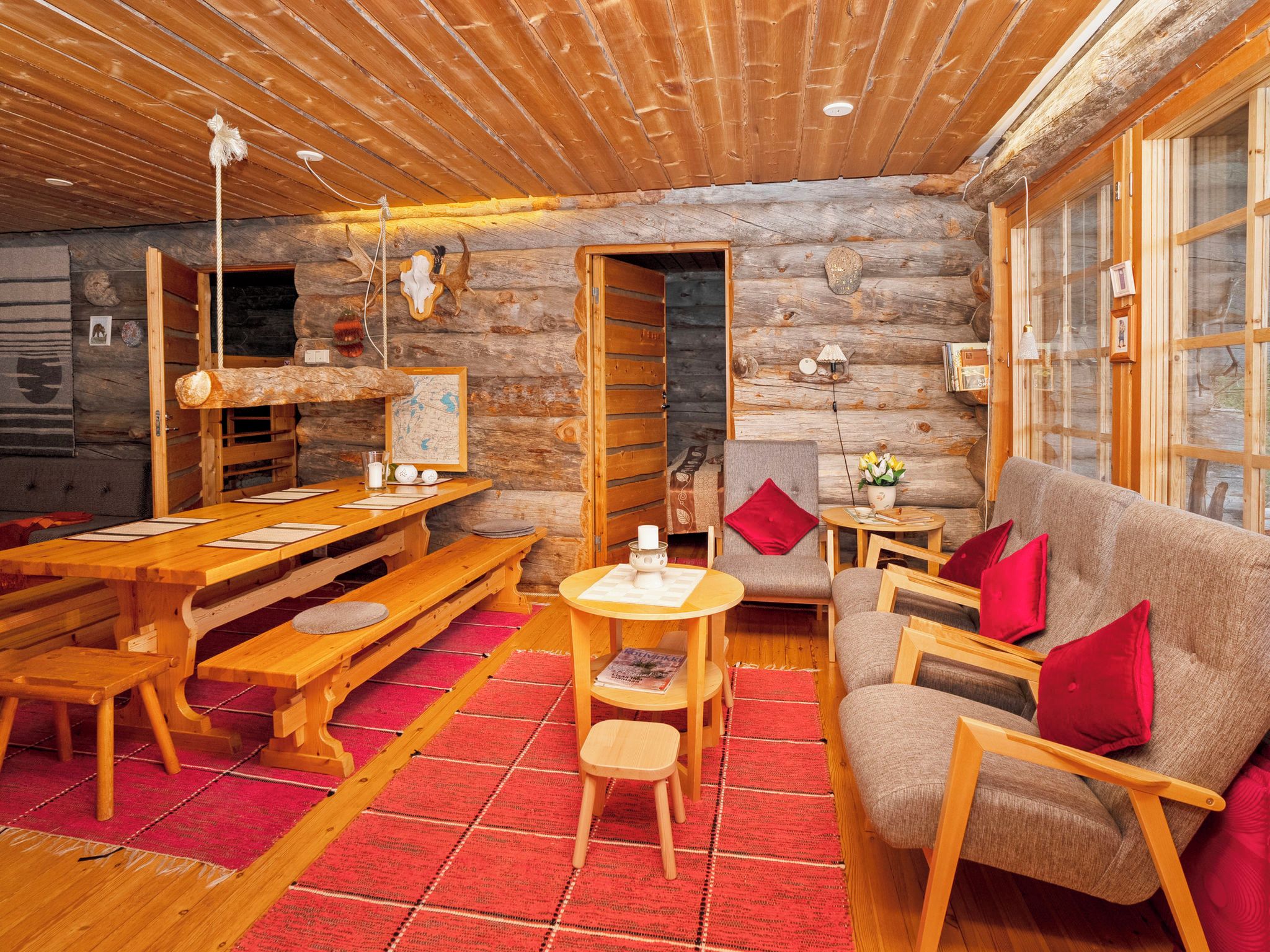 Interior de una cabaña de troncos con comedor, sofá y chimenea.