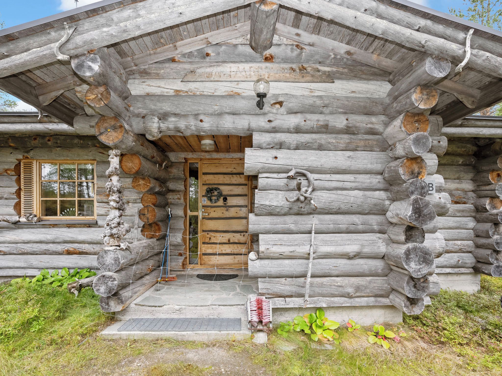 A log cabin with a wooden door, a window with shutters, and a porch area.