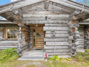 Une cabane en rondins avec une porte en bois, une fenêtre avec des volets et une véranda.