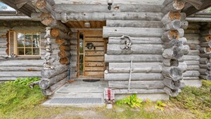 A log cabin with a wooden door, a window with shutters, and a porch with steps leading to the entrance.