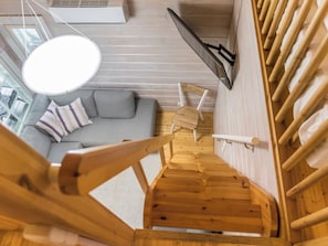 A modern interior with a wooden staircase leading to a living area with a gray sofa and striped pillows.