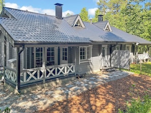 A single-story house with a covered porch, a chimney, and a fenced yard.