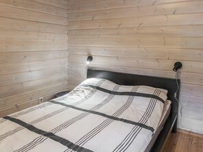 En enkeltseng med sort sengegavl i et rum med trævægge.