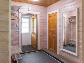 A narrow hallway with wooden walls, a wooden door, a window, and a door mat. - Sini 2b by Interhome (Sotkamo)