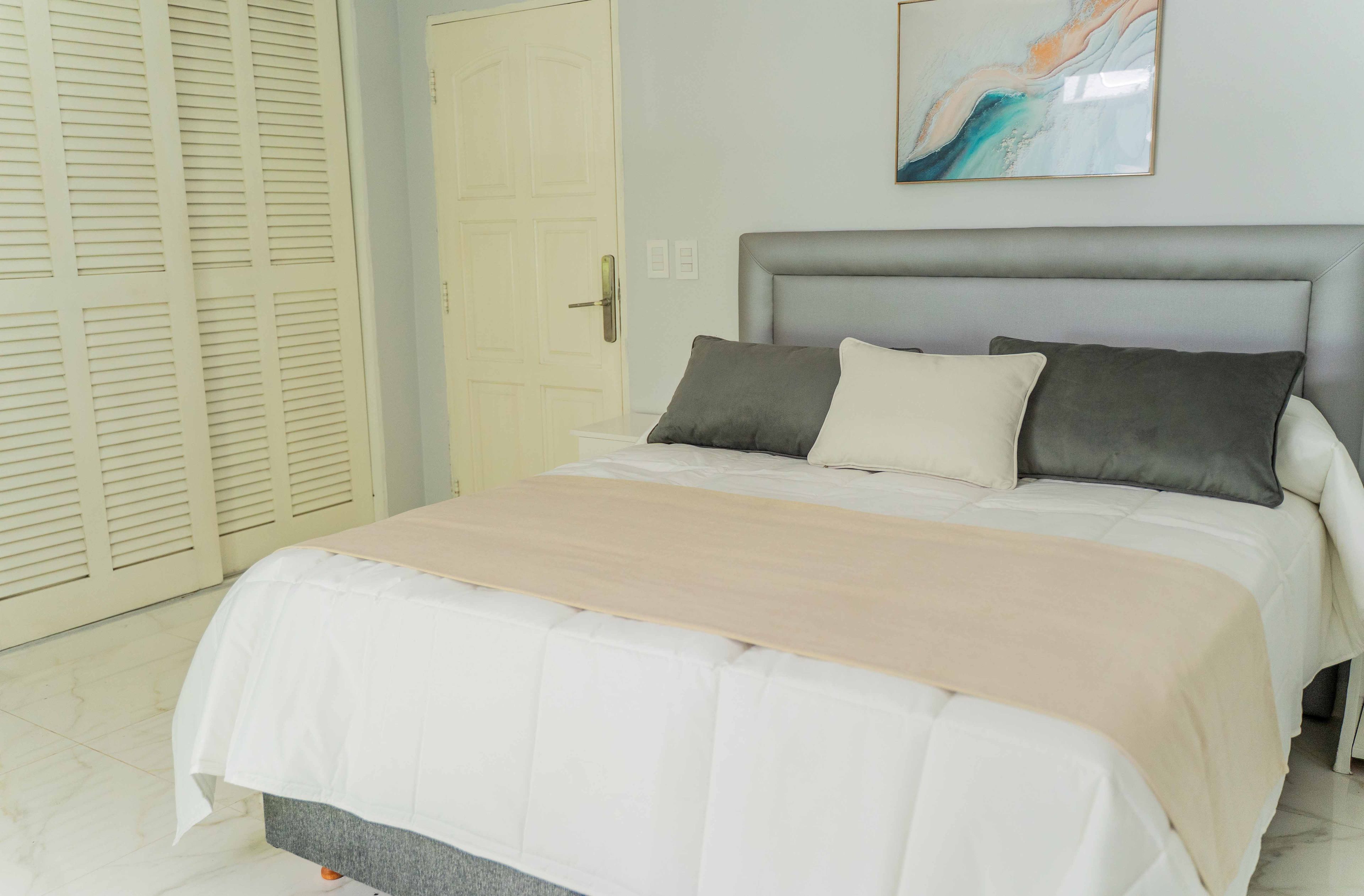 A bed with a grey headboard, white bedding, and two pillows.