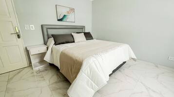 A bedroom with a bed, nightstands, a wall-mounted artwork, and a door.