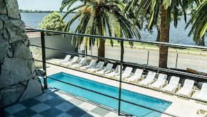 A poolside area with a checkered floor, white lounge chairs, and a view of the water. - Palmas de la Laguna by Posada Suiza (San Miguel del Monte)