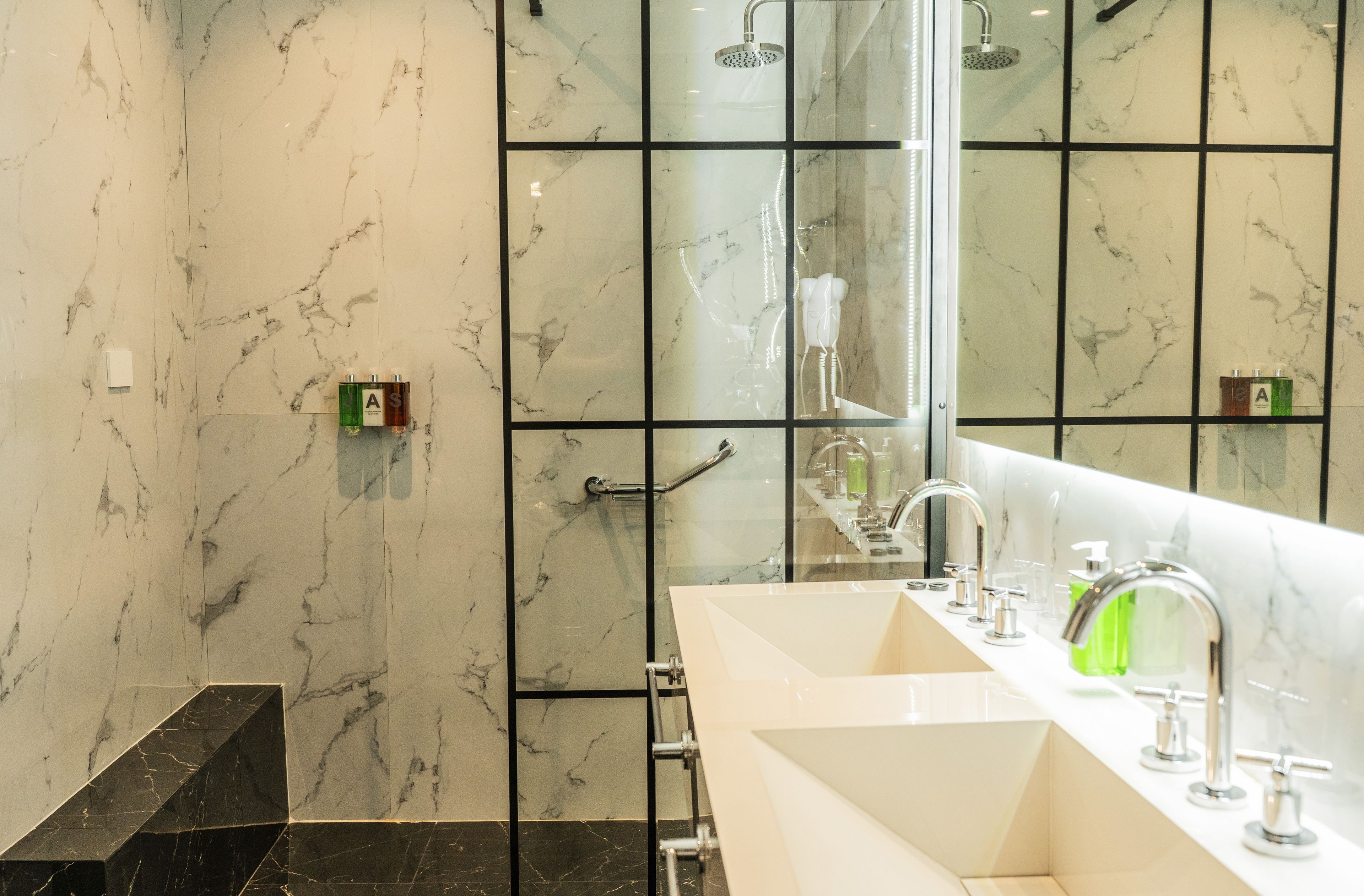 A modern bathroom with a large mirror, a dual sink vanity, and a shower area.