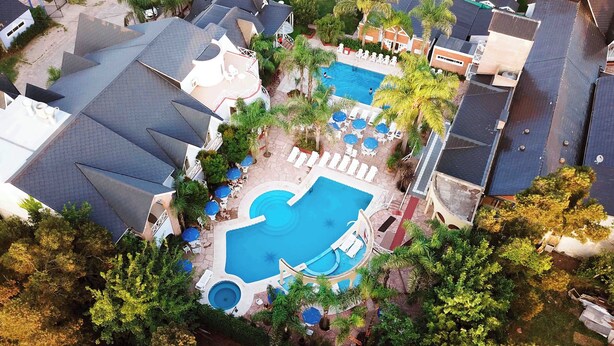 An aerial view of a residential area with a swimming pool surrounded by lounge chairs and umbrellas, indicating a resort-like setting. - Posada Suiza by Prima Collection (San Miguel del Monte)